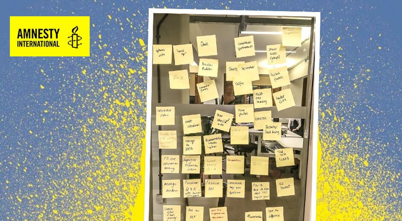 Glass wall full of post-it notes from a workshop with Amnesty International