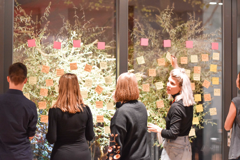 A group place post-it notes on a large glass wall